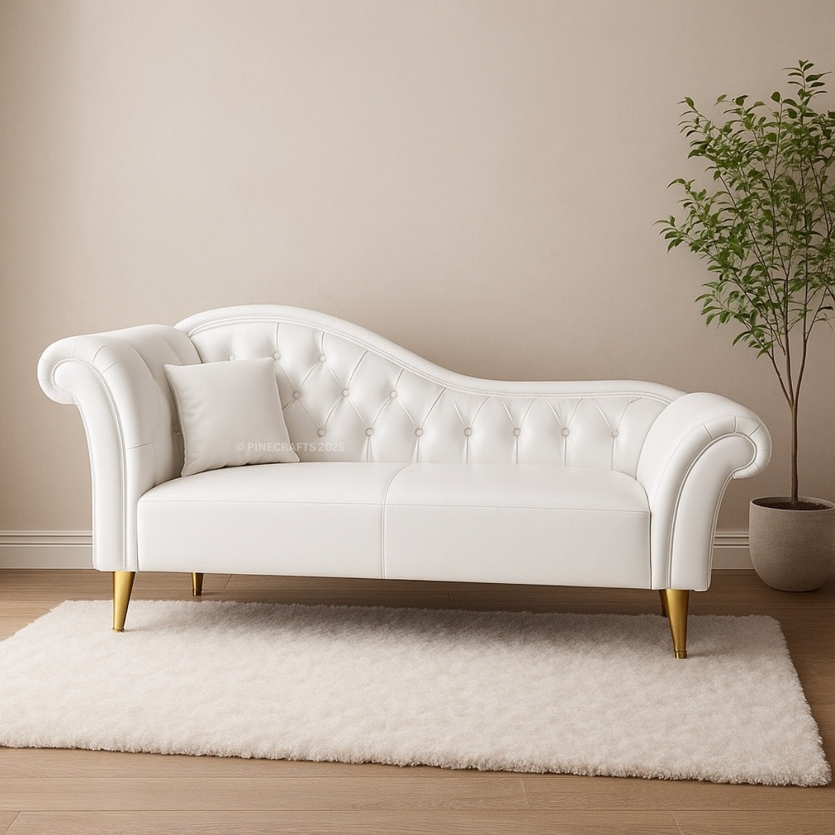 White tufted sofa with gold legs in a room with a beige wall and a plant.